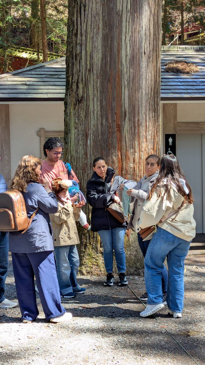 Small group chatting and waiting near a wooden pillar outside public facilities.