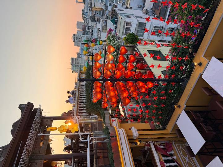 Rooftop café adorned with red lanterns at golden sunset overlooking city buildings