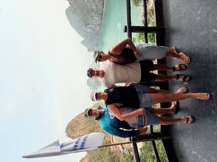 Group of four travelers posing at a balcony with dramatic karst islands and turquoise bay below