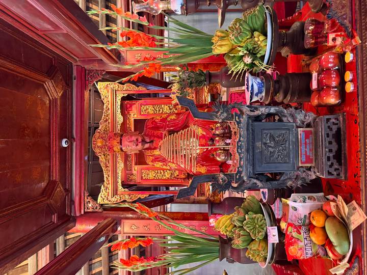 Vibrant red altar with ornate deity statue surrounded by offerings and flowers inside temple