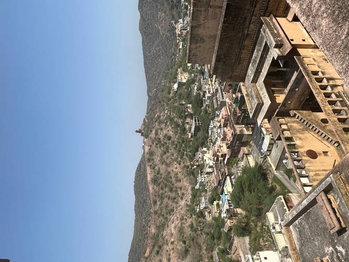 Panoramic view from Amber Fort over rugged hills and clustered village buildings.