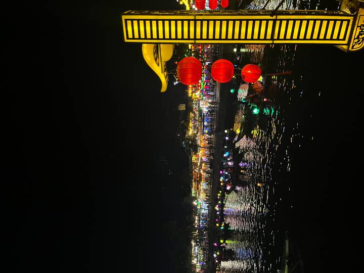 Nighttime lantern festival reflections on the river in Hoi An with glowing red lanterns in the foreground.