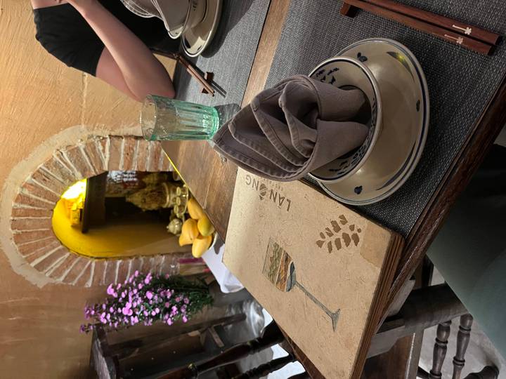 Cozy restaurant table set with folded napkin, rustic menu and fresh flowers against a warm brick alcove.