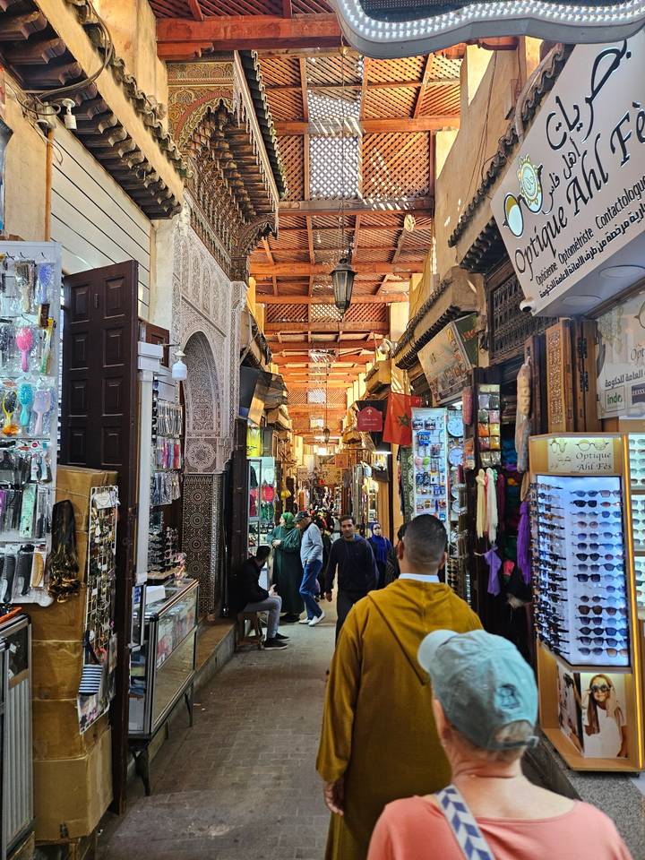 Busy vaulted souk corridor with intricate Moorish arch, colorful merchandise and shoppers.