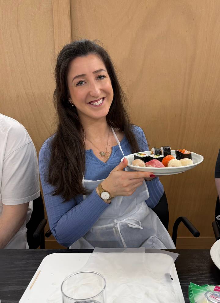 Participant proudly displays a plate of handmade sushi pieces during class.