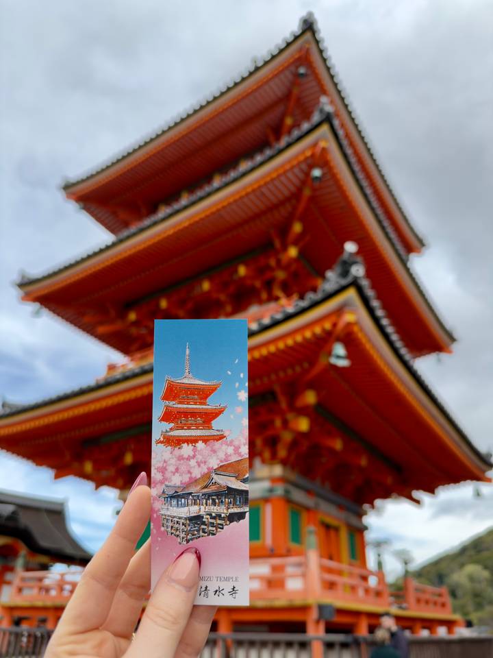 Art postcard of a red pagoda held up against the blurred backdrop of the actual pagoda.