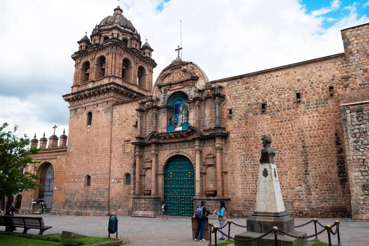 Historic stone church with ornate bell tower and turquoise wooden door in Cusco’s colonial center.