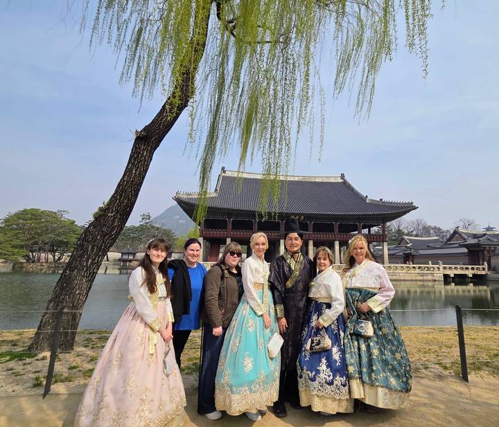 Visitors dressed in colorful hanbok pose beside the pond at Gyeongbokgung’s Gyeonghoeru Pavilion.