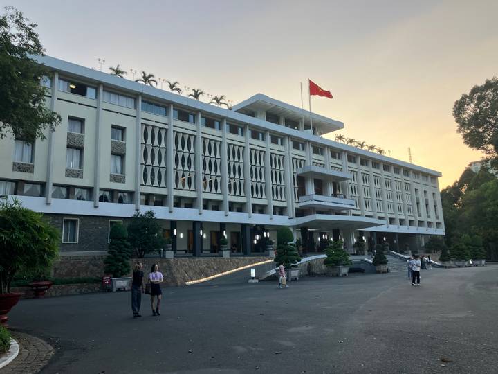 Vietnam’s Reunification Palace, a 1960s modernist government building, with visitors in front at dusk.