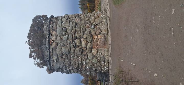 Large circular stone memorial cairn at historic battlefield site surrounded by moorland.