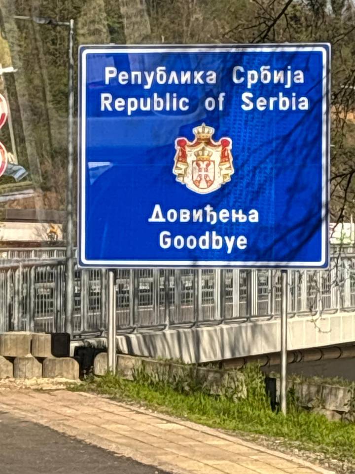 Close-up of a blue border sign saying goodbye in Serbian and English.