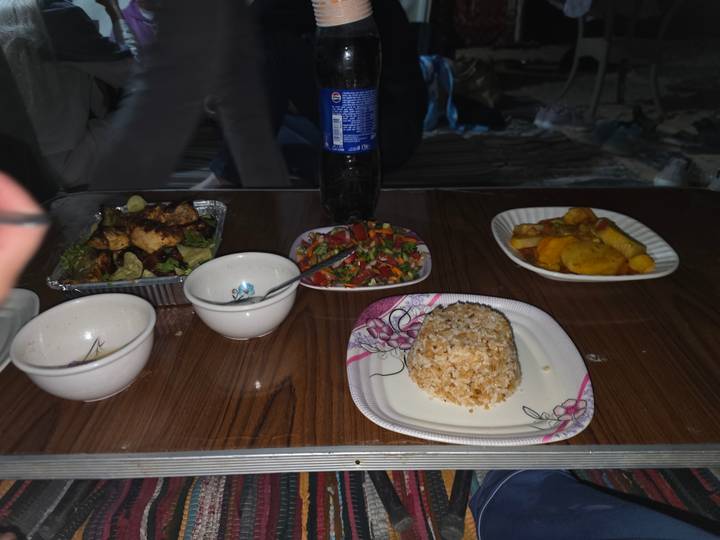Night-time camp table with simple dishes and soda bottle lit by flash.