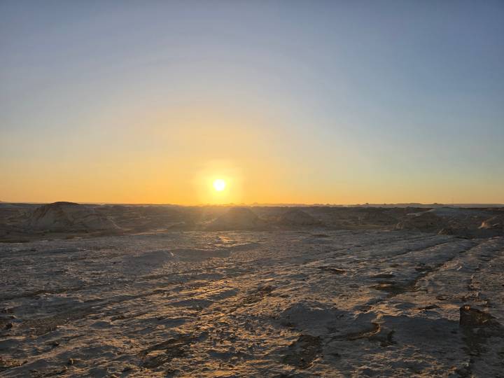 Sunset casts a warm glow over the rocky expanse of the White Desert.