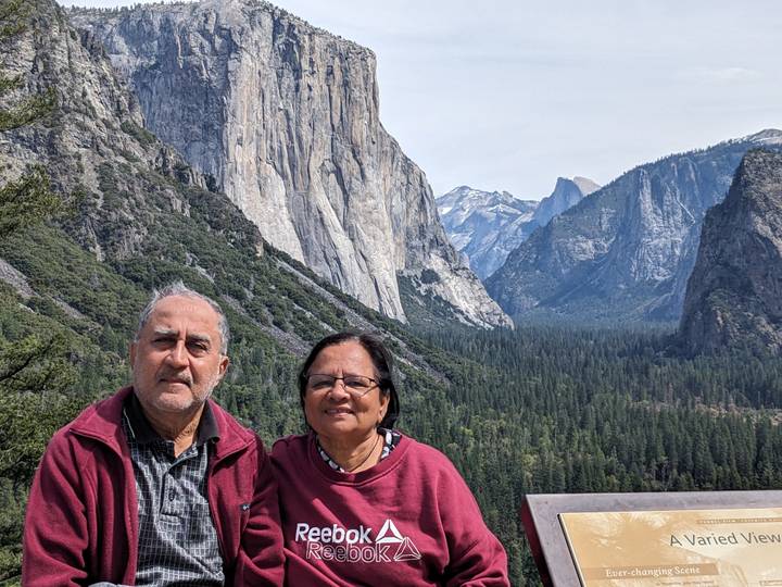 Smiling couple posed at Yosemite’s Tunnel View with El Capitan, Half Dome and dense forest backdrop.
