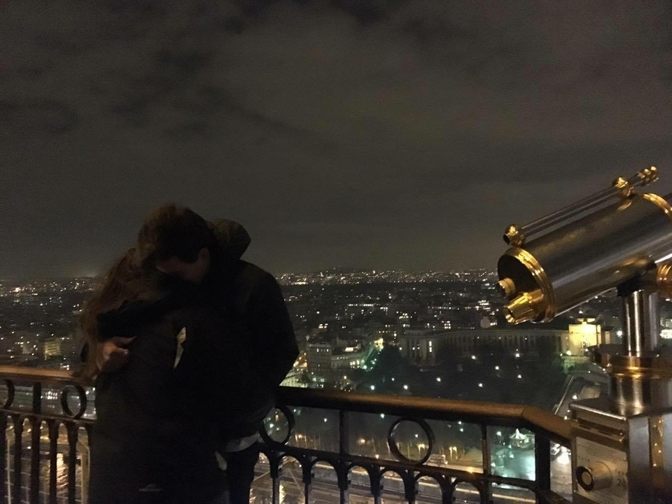 Couple embracing at night in a cityscape view.