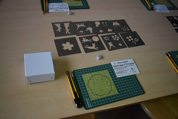 Workshop table displaying stencil templates, cutting mats and craft knives prepared for a class.