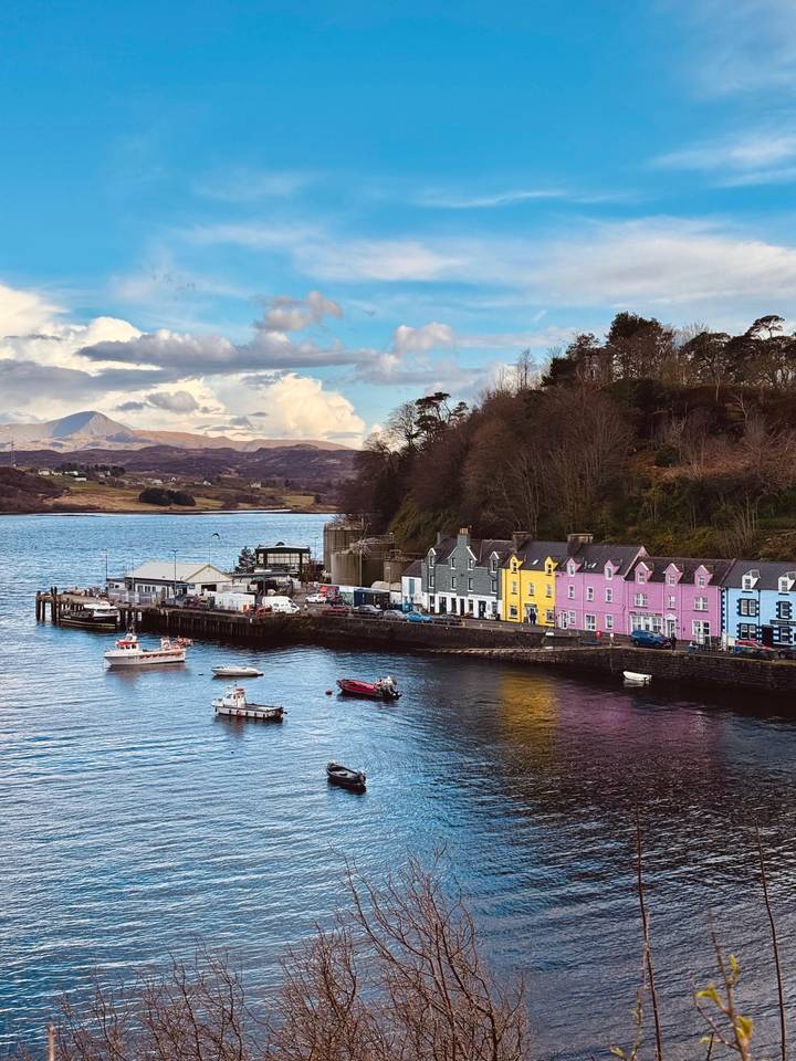 Colorful row of houses lines Portree’s waterfront with boats bobbing in the bay.