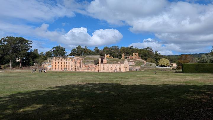 Historic sandstone penitentiary ruins at Port Arthur surrounded by lawns and scattered visitors.