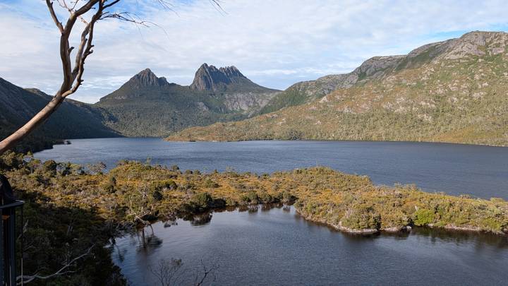 Iconic view of Cradle Mountain towering over reflective Dove Lake under patchy clouds.