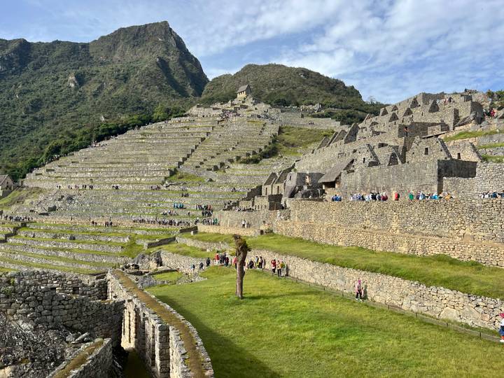 Extensive agricultural terraces of Machu Picchu with stone buildings and crowds below citadel.