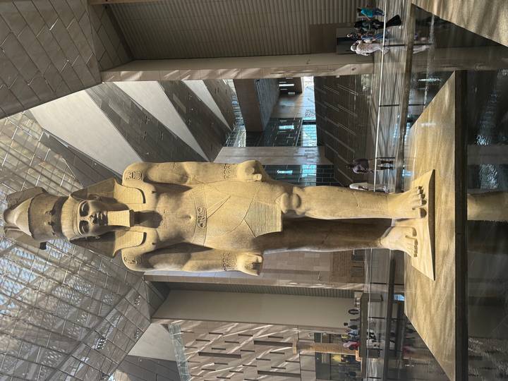Colossal statue of Pharaoh Ramses II dominates the skylit atrium of the Grand Egyptian Museum.