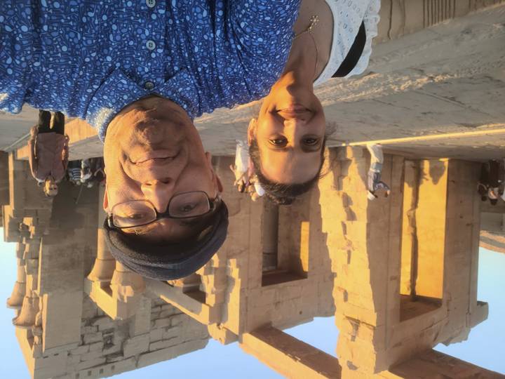 Man and woman posing in front of ancient sandstone columns at an Egyptian temple.
