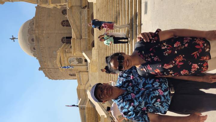Couple posing in front of a domed church in Cairo on a bright sunny day.