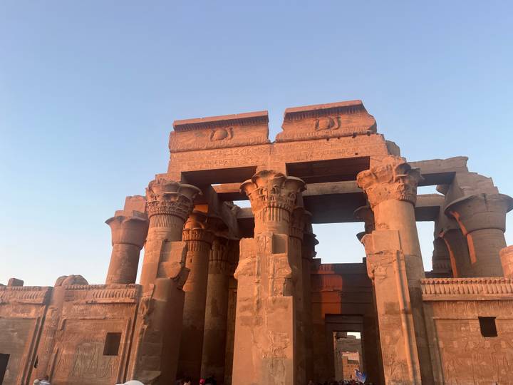 Kom Ombo Temple bathed in warm sunset light against a clear sky.