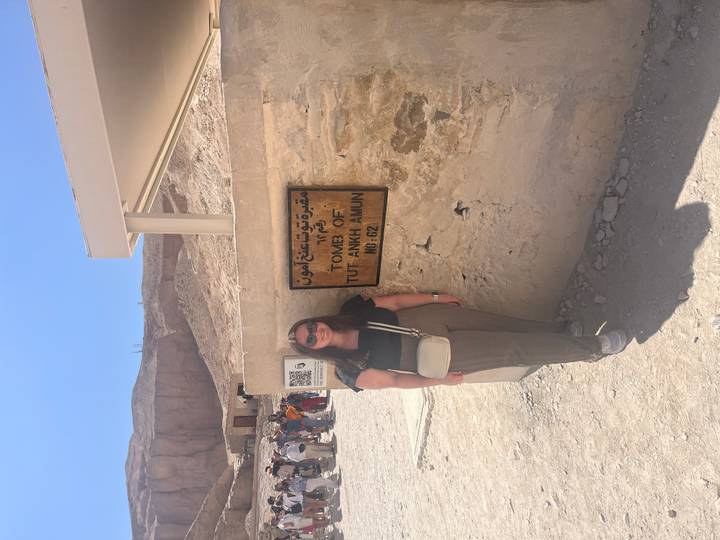 Traveler standing next to a sign for the Tomb of Tutankhamun in the Valley of the Kings.