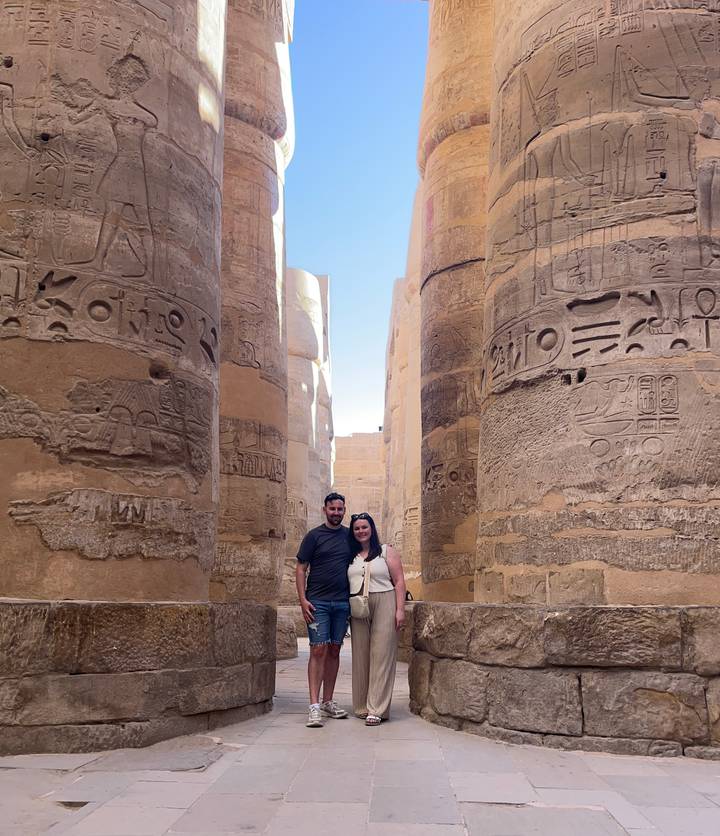 Couple surrounded by giant hieroglyph-covered columns inside Karnak Temple.
