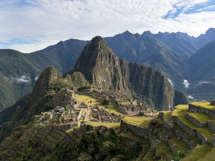 Panoramic view of the full Machu Picchu citadel with dramatic green peaks behind.