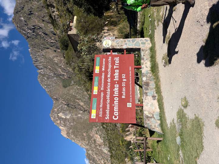 Welcome sign for the Inka Trail at the Machu Picchu historical sanctuary with mountains behind.