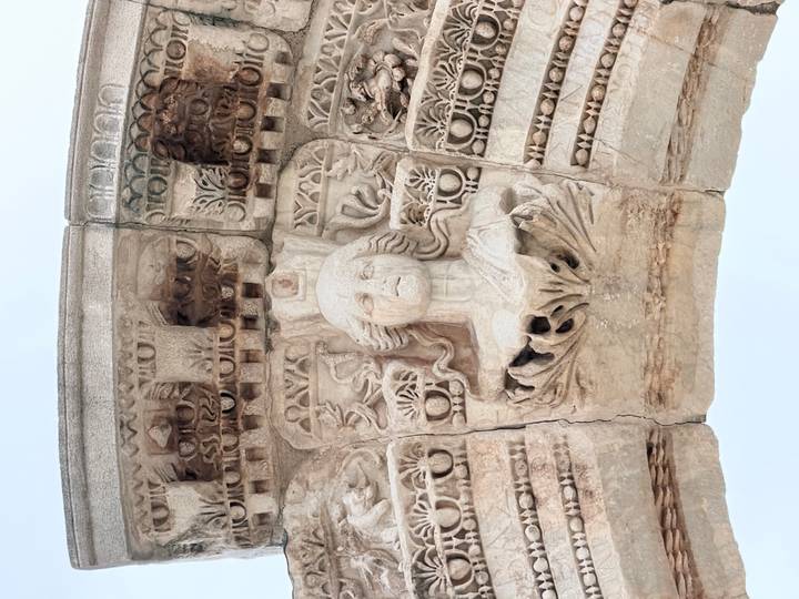 Close-up of a carved stone relief of a female figure on an ancient Roman arch.