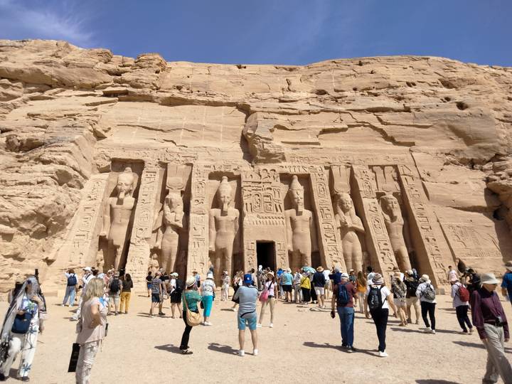 Crowd gathered before the Temple of Hathor at Abu Simbel, its colossal relief figures carved into sandstone cliffs