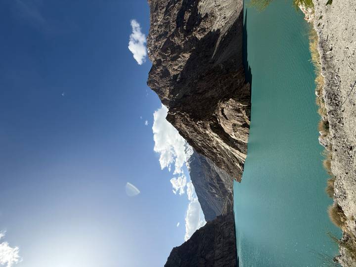 Turquoise lake surrounded by rugged brown mountains under a clear deep-blue sky