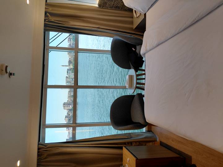 Modern cabin bedroom on a Nile cruise ship with two chairs and panoramic window overlooking the river and distant minaret