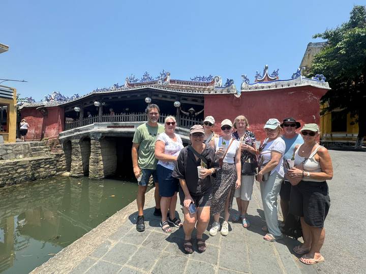 Tour group standing in front of Hoi An’s red Japanese Covered Bridge on a bright day