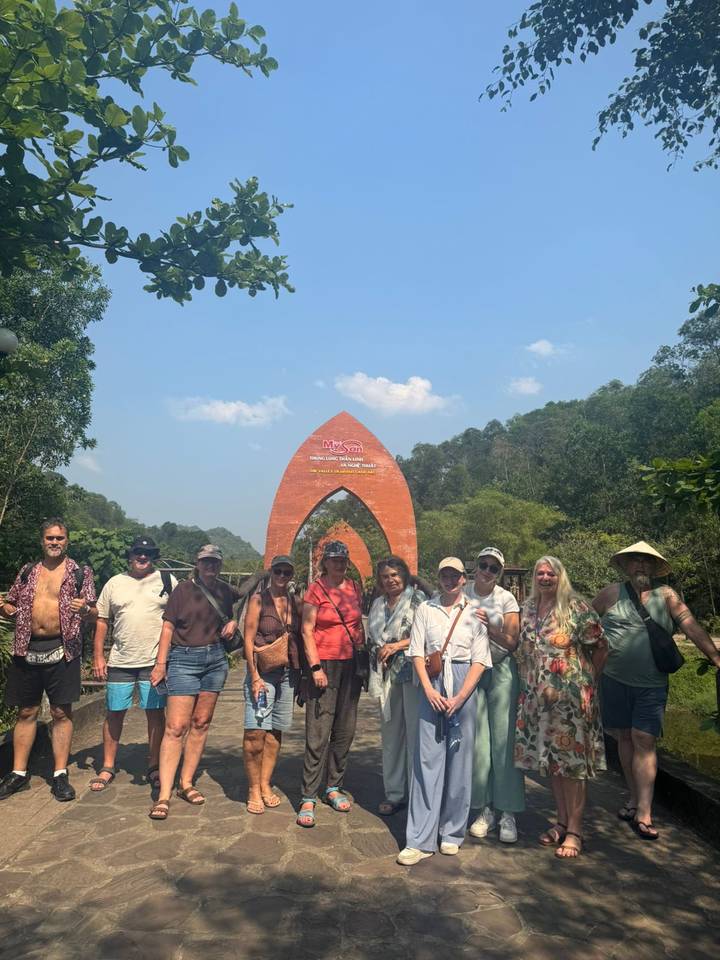 Large group posing beneath the brick arch entrance sign of My Son Sanctuary