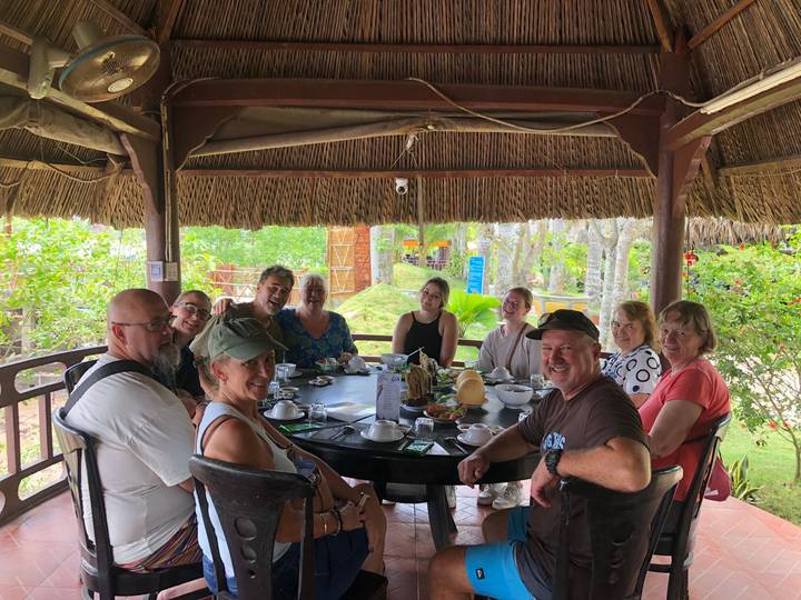 Group gathered around a circular dining table enjoying Vietnamese dishes in an open pavilion