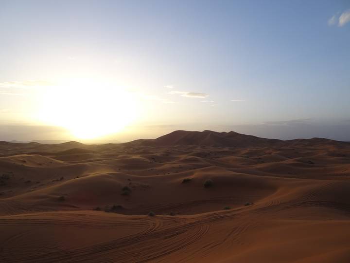 Golden sun setting over rolling Sahara sand dunes creating long shadows and soft light