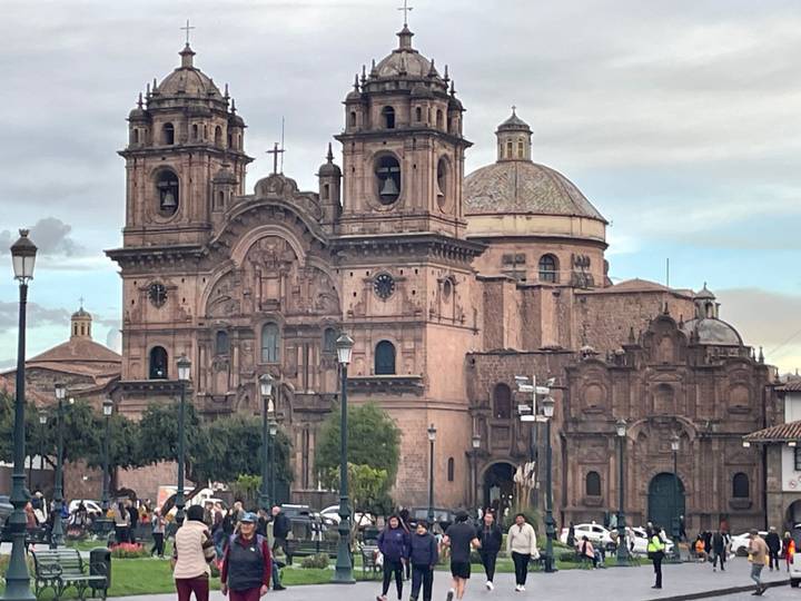 Historic stone cathedral with two bell towers and dome dominates a busy plaza under cloudy skies