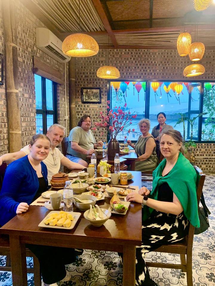 Small group of travellers sharing a traditional meal inside a cosy brick-walled restaurant with lanterns.