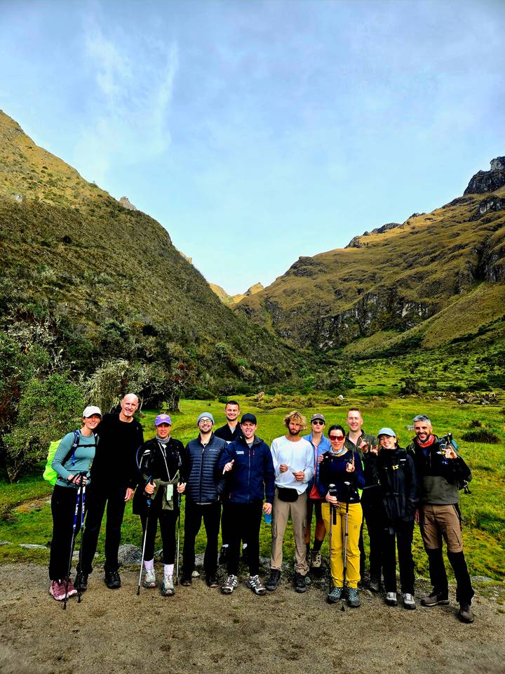 Hikers posed in a green Andean valley surrounded by steep hillsides