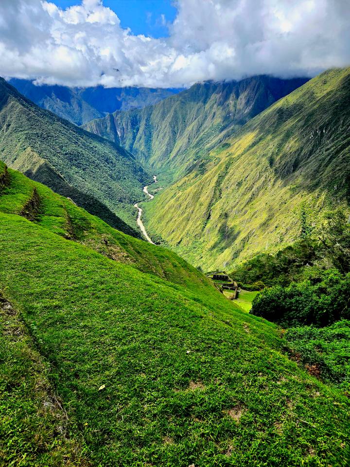 Steep emerald slopes descending to a winding river deep in the Andean valley