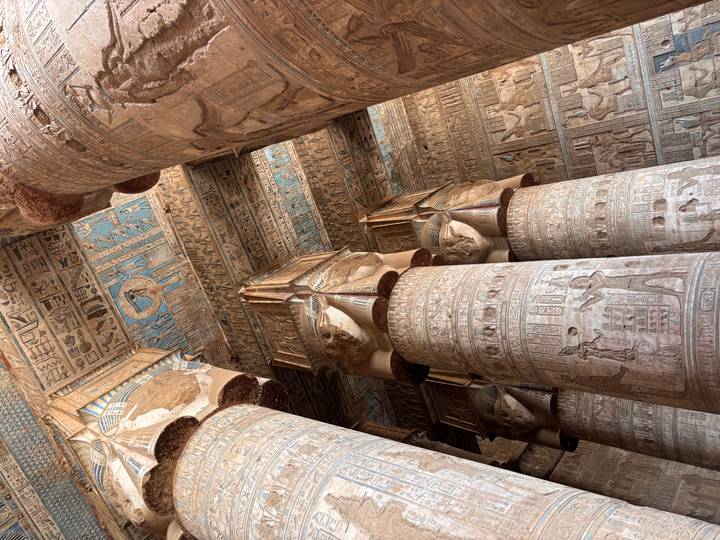 Interior view of temple hypostyle hall with towering carved columns and blue painted ceilings