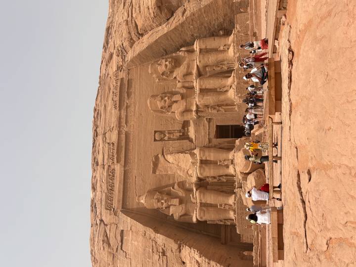 Massive rock-cut façade of Abu Simbel temple with colossal statues and crowds of visitors below