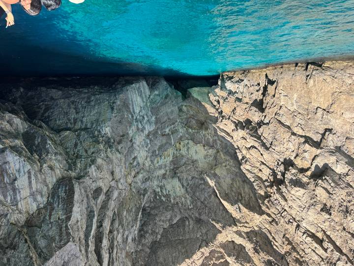 Turquoise water inside a dramatic sea cave with rugged limestone walls lit by sunlight.