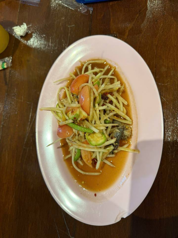 Plate of Thai green papaya salad with tomatoes and long beans dressed in zesty sauce.