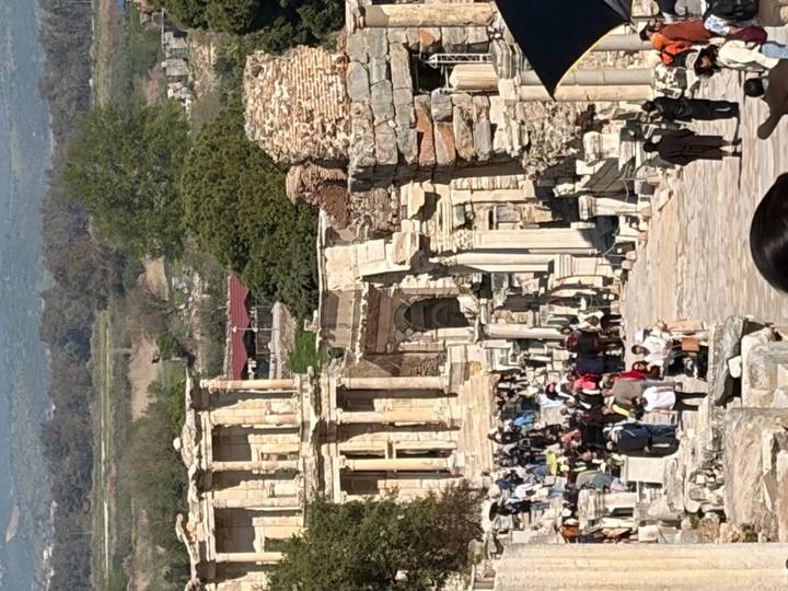 Crowds exploring stone ruins and columns of ancient Ephesus street