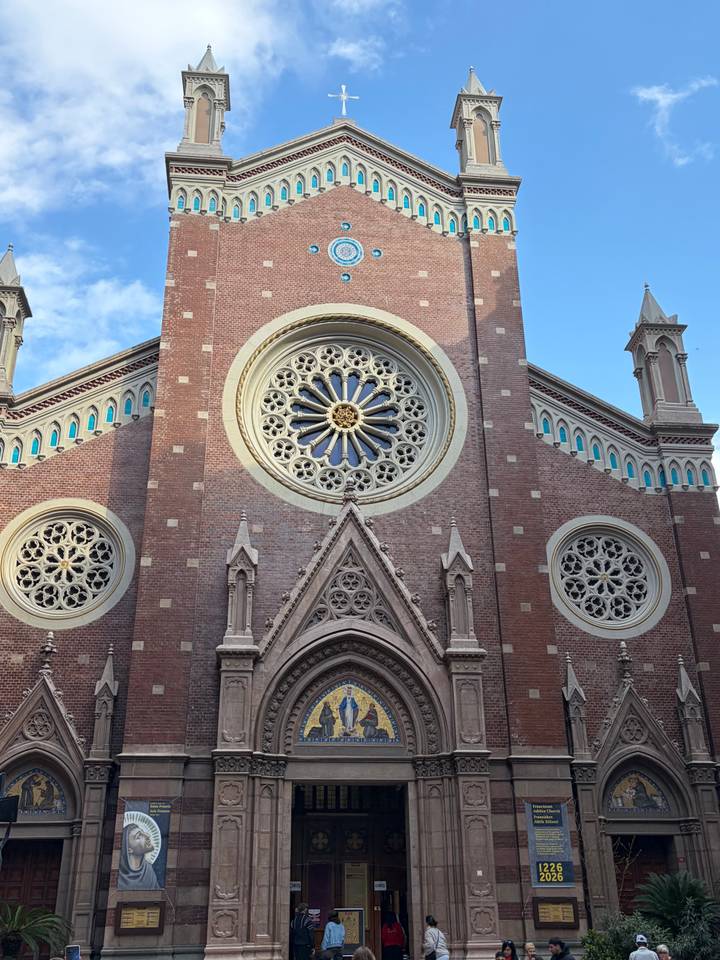 Neo-Gothic brick church façade with large rose windows and pointed arches